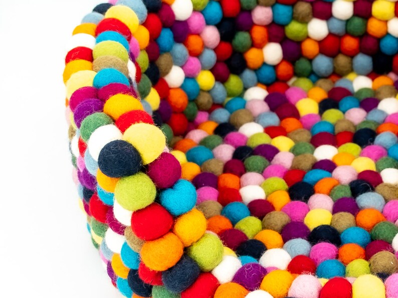 Pu&ograve; includere: Un letto rotondo per animali domestici colorato fatto di palline di feltro. Il letto &egrave; fatto di una variet&agrave; di colori, tra cui rosso, blu, verde, giallo, arancione, viola e bianco.