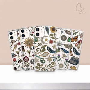 Puede incluir: Una colección de fundas transparentes para teléfonos con varios diseños caprichosos. Cada funda presenta un patrón único de ilustraciones celestiales, botánicas e inspiradas en lo vintage en blanco, dorado y azul. Las fundas se exhiben sobre una superficie blanca.