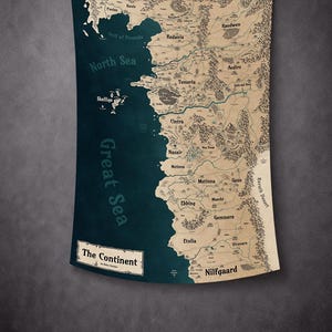 May include: A wall tapestry featuring a detailed map of a fictional continent. The map is in shades of beige and brown, with a dark blue sea and text labels. The title "The Continent" is at the bottom.