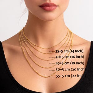 May include: Gold-colored chain necklaces of varying lengths are displayed. The chains range from 14 inches (35+5 cm) to 22 inches (55+5 cm) in length. The image shows the necklaces against a person's upper body.