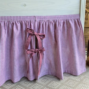 May include: A gathered curtain panel featuring a mauve and white vertical striped pattern. The fabric is split in the center and secured with two matching mauve fabric bows tied in a knot, creating a decorative opening along the front edge.