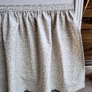 May include: A white ceramic mug with a black handle and the text "But First, Coffee" in a black, handwritten-style font. The mug is on a white surface.