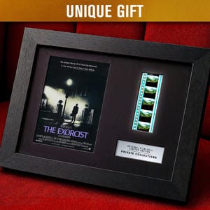 May include: Framed black artwork featuring a movie poster and film cell from "The Exorcist." The poster is black and white, with the film title at the bottom. The film cell shows a series of green and blue frames. The text "UNIQUE GIFT" is at the top.