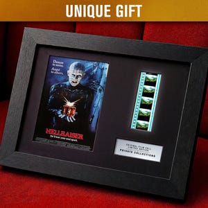 May include: Framed Hellraiser movie poster print with film cell strip. The black frame holds the poster, film strip, and a plaque that reads "Original Film Cell Limited Edition Private Collections". The poster features a character holding a gift box.