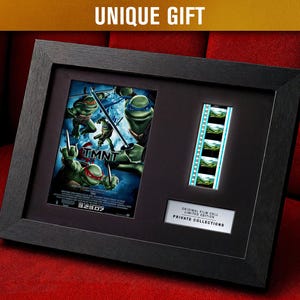 May include: Framed TMNT movie poster print with a film cell strip. The black frame holds the poster, film strip, and a small plaque that reads "ORIGINAL FILM CELL LIMITED EDITION PRIVATE COLLECTIONS". The poster features the Teenage Mutant Ninja Turtles.
