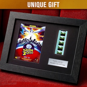 Può includere: Cornice nera che incornicia un poster del film Pokémon 2000 e una cella cinematografica. Il poster ha uno sfondo rosso e blu con il testo "Pokémon 2000" e "21 luglio". La cella cinematografica mostra una serie di immagini verdi. La cornice ha il testo "UNIQUE GIFT".