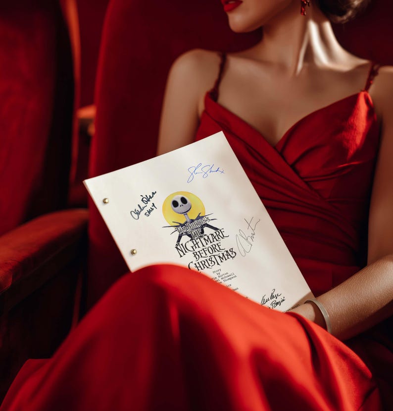 May include: A script for "The Nightmare Before Christmas" with signatures, held by a person wearing a red dress. The script features the film's title and a graphic of Jack Skellington. The background is a red theater seat.