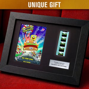 Op de afbeelding: Zwart ingelijst kunstwerk met een filmposter van "The SpongeBob SquarePants Movie" en een filmstrip. De poster is kleurrijk met stripfiguren. De lijst is zwart en de tekst "UNIQUE GIFT" staat bovenaan.