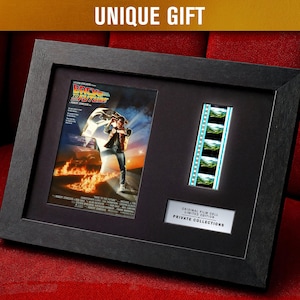 Puede incluir: Enmarcado con un póster de la película "Regreso al Futuro" con una tira de película y el texto "UNIQUE GIFT". El marco negro contiene el póster, la tira de película y una placa que dice "ORIGINAL FILM CELL LIMITED EDITION PRIVATE COLLECTIONS".