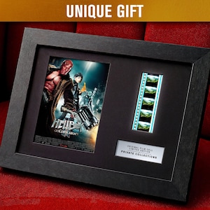 May include: Framed Hellboy movie poster with a film strip and the text "UNIQUE GIFT". The black frame holds the poster and film cell, with a label that reads "ORIGINAL FILM CELL LIMITED EDITION PRIVATE COLLECTIONS". The poster features Hellboy and other characters.