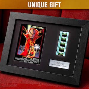 Puede incluir: Enmarcado en negro con recuerdos de películas, incluyendo un póster y una tira de película. El póster es de la película "Flash Gordon", con tonos rojos y amarillos. El marco tiene un acabado negro, y el texto "UNIQUE GIFT" está en la parte superior.