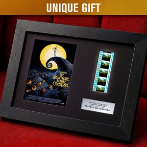 Op de afbeelding: Zwart ingelijst kunstwerk met een filmposter en filmstrook van "The Nightmare Before Christmas". De poster toont Jack Skellington op een heuvel met een volle maan. De lijst bevat de tekst "UNIQUE GIFT".