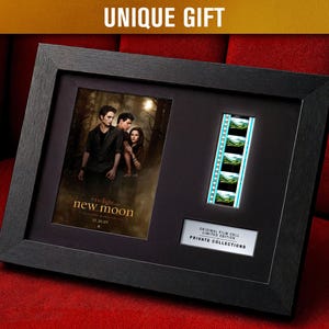 May include: Black framed artwork with a film poster and film strip. The poster is for "Twilight: New Moon" with the date 11.20.09. The film strip has four frames. The text "UNIQUE GIFT" is at the top, and "ORIGINAL FILM CELL LIMITED EDITION PRIVATE COLLECTIONS" is at the bottom.