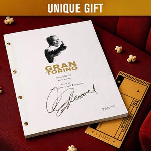 Puede incluir: Un guion blanco con el título "Gran Torino" y una imagen en blanco y negro de un hombre. El guion está firmado y tiene encuadernación dorada. También se ve una entrada de cine vintage y palomitas de maíz.