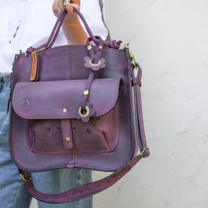 This leather bag is made with additional extra original leather tassel handmade flowers. Bag has decorative outside big pocket. Is top handle bag with tied leather handles. Bag is made in Plum matte natural thick leather.