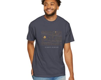 May include: A dark gray short-sleeved t-shirt featuring a gold-colored line art graphic of celestial and architectural elements, including a crescent moon and stars, with the text "AS ABOVE, SO BELOW" printed in white lettering underneath.
