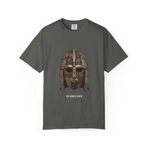 May include: A charcoal gray short-sleeve t-shirt featuring a graphic of a weathered, metallic gold and dark brown historical helmet centered on the chest. Below the helmet, the text reads THE KING'S HELM in white capital letters.