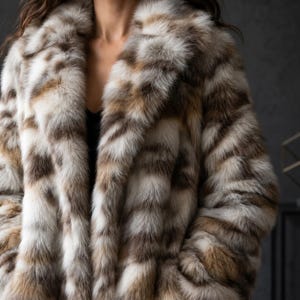 Puede incluir: Un lujoso abrigo de piel con un llamativo patrón de marrón, blanco y beige. El abrigo presenta un cuello ancho y un aspecto suave y texturizado. El diseño es una mezcla de rayas verticales y horizontales, creando un atractivo visual único. Ideal para el invierno.