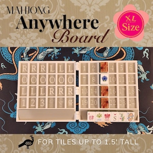 May include: A white folding Mahjong Anywhere Board with a grid for tiles, featuring text 'MAHJONG Anywhere Board' and 'XL Size'. The board includes numbered and lettered slots, with several decorative tiles placed inside. Text reads 'FOR TILES UP TO 1.5' TALL'.