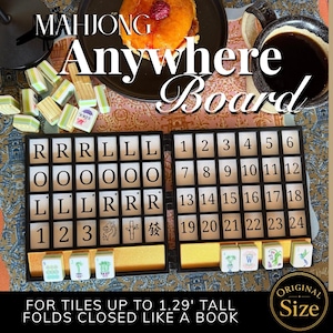May include: A black folding Mahjong Anywhere Board with a grid of letters and numbers, featuring slots for tiles. The board displays text reading Mahjong Anywhere Board and Original Size, with a note stating it is for tiles up to 1.29 inches tall.