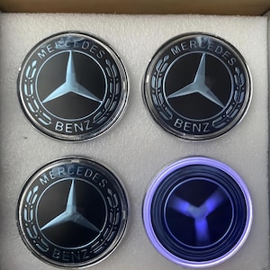 May include: A white ceramic mug with a black handle and the text "But First, Coffee" in a black, bold font. The mug is on a white surface.