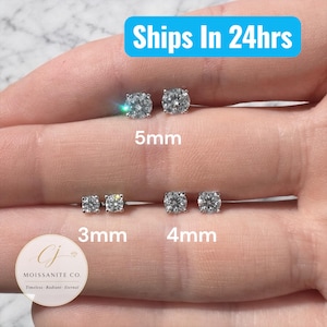 May include: A selection of moissanite stud earrings in 3mm, 4mm, and 5mm sizes. The earrings are round-cut and set in a silver or white metal. The image includes the text "Ships In 24hrs" and the brand logo "Moissanite Co."