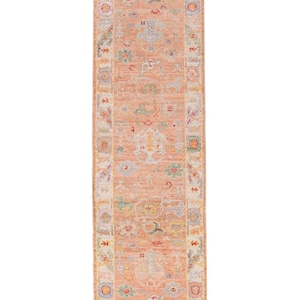 May include: A rectangular, peach-coloured rug with an intricate floral pattern. The rug features a central design with a border of various colours, including green, blue, and yellow. The rug is designed for a hallway or entryway.
