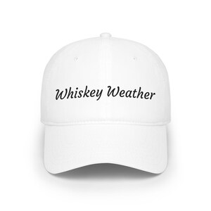 Peut inclure: Une casquette de baseball blanche avec le texte Whiskey Weather imprimé en police cursive noire sur le panneau avant. La casquette présente une calotte structurée, une visière incurvée et un bouton au sommet, offrant un design épuré.
