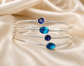 Puede incluir: Cuatro brazaletes finos de plata, cada uno con una piedra preciosa facetada. Dos pulseras tienen piedras redondas de color azul intenso, mientras que las otras dos presentan piedras ovaladas de color azul turquesa brillante. Son lisos.