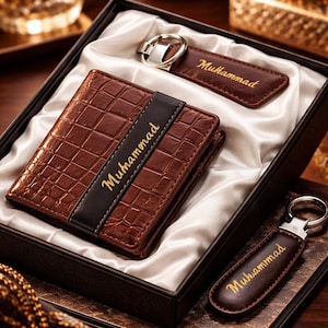 May include: A brown leather wallet, keychain, and key ring set in a gift box. The wallet and keychains are embossed with a crocodile pattern and the name "Muhammad" in gold lettering. The set is presented on a white satin lining.
