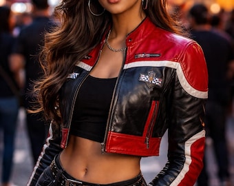 May include: A cropped black, red, and white leather jacket with a checkered emblem. The jacket is paired with a black top and dark-wash jeans. The model is wearing a gold chain necklace and hoop earrings.