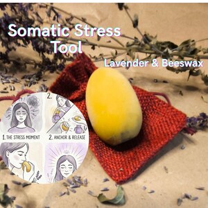 Könnte beinhalten: Ein gelbes, eiförmiges Somatic Stress Tool aus Lavendel und Bienenwachs, das auf einem kleinen roten Beutel liegt. Der Text lautet "Somatic Stress Tool Lavender & Beeswax". Ein Diagramm zeigt die Anwendung.