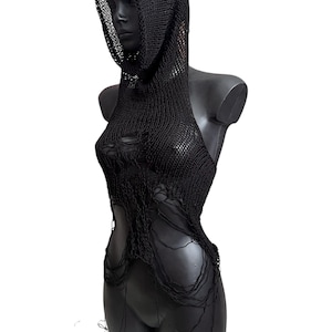May include: Black knitted halter top with a hood. The top features a distressed design with open areas and dangling threads. The garment is displayed on a black mannequin against a white background.