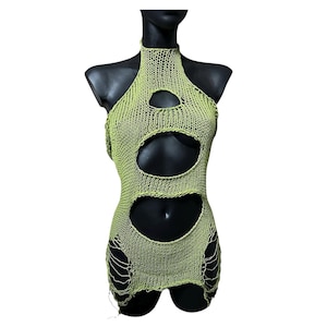 Può includere: Abito a collo alto verde lime con grandi dettagli ritagliati. L'abito è realizzato in materiale a maglia e ha una scollatura alta. I ritagli si trovano sul petto e sull'addome e l'orlo è irregolare.