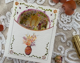 May include: A square greeting card with a die-cut circular window revealing a layered 3D scene of a birthday celebration with a person, cake, and bunting. The front features a watercolour illustration of a vase with colourful flowers and vines.