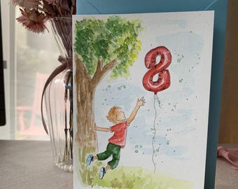 May include: A greetings card featuring a watercolour illustration of a child in a red shirt and green trousers reaching for a red balloon shaped like the number eight. The scene includes a tree and a light blue sky, presented with a blue envelope.