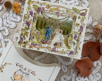 May include: A layered paper shadow box card featuring a watercolour illustration of a couple in a vineyard with a banner reading JUST MARRIED. A separate card shows two wine glasses and the text Mr & Mrs in a decorative script font.