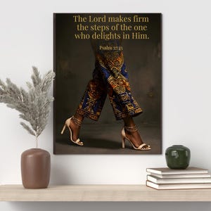 May include: A framed canvas print featuring a person's legs in patterned pants and high heels. The pants are blue with gold and orange designs. The heels are beige. The text on the canvas reads, "The Lord makes firm the steps of the one who delights in Him. Psalm 37:23."