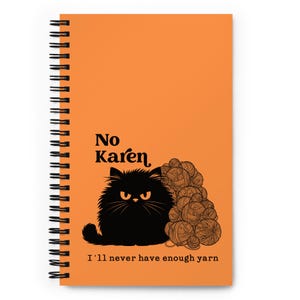 May include: An orange spiral-bound notebook featuring a black cat illustration and the text "No Karen, I'll never have enough yarn." The cat has an angry expression and is next to a pile of yarn balls.