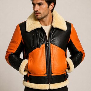 Puede incluir: Chaqueta de cuero negra y naranja con cuello y puños de borrego color crema. La chaqueta tiene cremallera, dos bolsillos delanteros y detalles en cuero negro. Chaqueta de estilo aviador clásico.