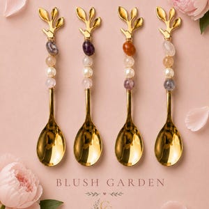 May include: Four gold-toned spoons with handles featuring a branch-like top and a series of four decorative beads in various colors and textures. The text BLUSH GARDEN and GIFTED & CO. DETAILS THAT LAST is printed below the spoons.