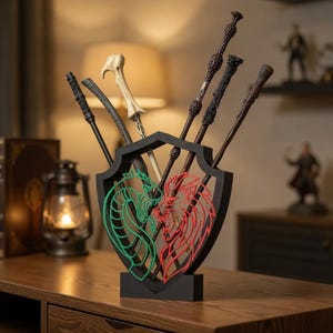 May include: A black shield-shaped wand holder with green and red accents, featuring a lion and snake design. Several wands of varying colors and designs are displayed in the holder, creating a decorative display.