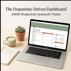 May include: A MacBook Pro laptop showing a Notion dashboard, a notebook, a cup of matcha latte, and a small potted succulent. The screen displays "The Dopamine-Driven Dashboard ADHD Productivity System for Notion".