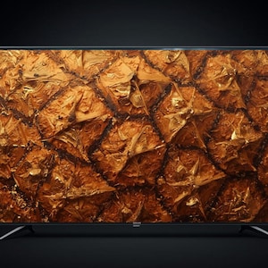 May include: A large flat-screen television with a textured, abstract display in shades of gold and brown. The screen is set against a black background, with thin silver legs supporting the TV.