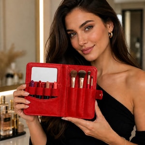 May include: A red makeup brush and lipstick organizer with a mirror. The organizer holds several makeup brushes with gold handles and various lipsticks. The organizer is made of red leather-like material.