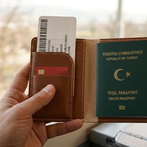 May include: A brown leather passport holder with a Turkish green passport and a boarding pass. The passport has a crescent moon and star symbol. A red credit card is visible in a pocket.