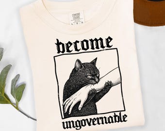 Camiseta divertida con estampado de gato mordiendo una mano, estilo vintage, con la frase "Become Ungovernable", camiseta con estampado de gato negro, camiseta con meme, regalo gótico para amantes de los gatos, camiseta con estampado de gatos graciosos.