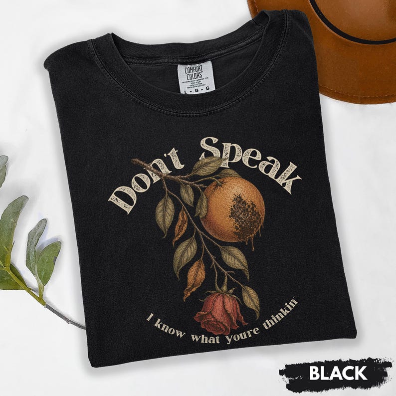 May include: Black t-shirt with a vintage-style botanical design. The graphic features a stylized orange fruit, leaves, and a rose, with the words "Don't Speak" and "I know what youre thinkin".