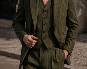 May include: An olive green three-piece suit featuring a blazer, a button-up vest, and matching trousers, all detailed with thin vertical pinstripes. The blazer has notched lapels, and the vest is fastened with five dark buttons down the front.
