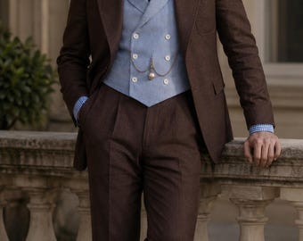 May include: A brown suit consisting of a jacket and trousers, paired with a light blue double-breasted waistcoat, a blue and white gingham shirt, and a dark red and navy striped tie. A pocket watch chain is attached to the waistcoat.